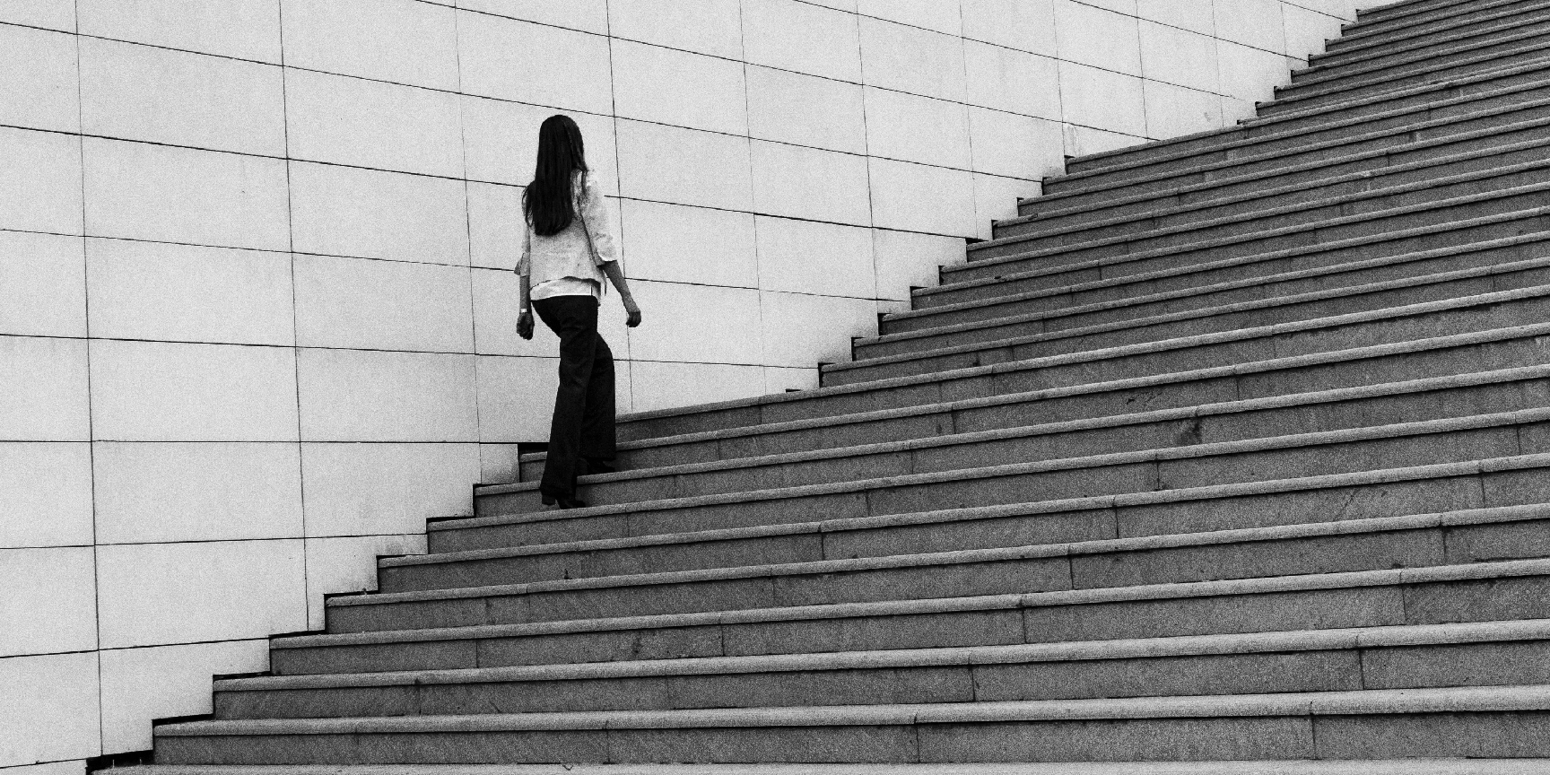 A black and white image of a young woman walking up some steps.
