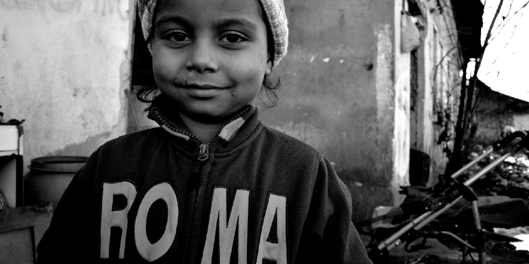 A young Roma girl in a sweater which reads “ROMA”